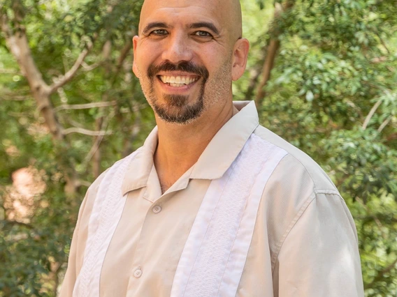 Photo of Dr. Martinez posed with greenery in the background.