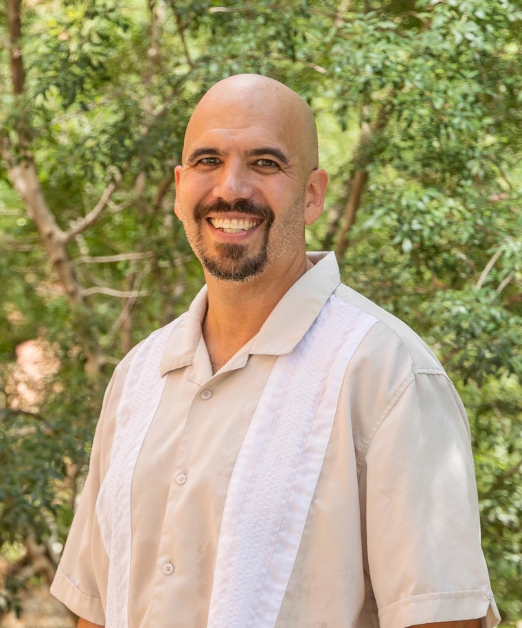 Photo of Dr. Martinez posed with greenery in the background.
